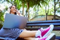 Beautiful young woman sitting in public park working on laptop computer Royalty Free Stock Photo