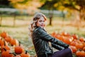 Beautiful young woman sitting on a pumpkin`s field. Autumn background Royalty Free Stock Photo
