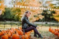 Beautiful young woman sitting on a pumpkin`s field. Autumn background Royalty Free Stock Photo