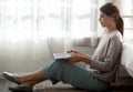 Beautiful young woman sitting side bed using laptop computer to online with comfortable and cozy in the bedroom. Royalty Free Stock Photo