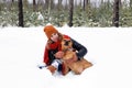 Beautiful young woman is sitting on a snow and playing with her American Staffordshire Terrier dog in winter coniferous forest Royalty Free Stock Photo