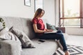 Beautiful young woman sitting on sofa and using laptop at home Royalty Free Stock Photo