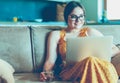 Beautiful young woman sitting on a sofa and working on a laptop Royalty Free Stock Photo