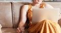 Beautiful young woman sitting on a sofa and working on a laptop Royalty Free Stock Photo