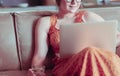 Beautiful young woman sitting on a sofa and working on a laptop Royalty Free Stock Photo