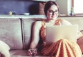 Beautiful young woman sitting on a sofa and working on a laptop Royalty Free Stock Photo