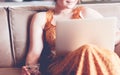 Beautiful young woman sitting on a sofa and working on a laptop Royalty Free Stock Photo