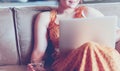 Beautiful young woman sitting on a sofa and working on a laptop Royalty Free Stock Photo