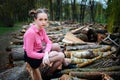 Beautiful young woman sitting on stack of felled tree trunks in the forest Royalty Free Stock Photo