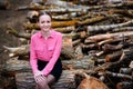 Beautiful young woman sitting on stack of felled tree trunks in the forest Royalty Free Stock Photo