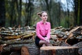 Beautiful young woman sitting on stack of felled tree trunks in the forest Royalty Free Stock Photo