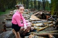 Beautiful young woman sitting on stack of felled tree trunks in the forest Royalty Free Stock Photo