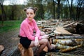 Beautiful young woman sitting on stack of felled tree trunks in the forest Royalty Free Stock Photo