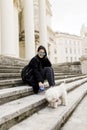 Beautiful girl sitting on stairs with her pet dog after walk in Royalty Free Stock Photo