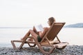 The beautiful young woman sitting on the sun lounger reading a book Royalty Free Stock Photo