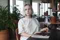 Beautiful young woman sitting at table holding in hand glass of drink at restaurant. Blonde pretty lady Royalty Free Stock Photo