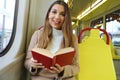 Beautiful young woman sitting in tram caught and surprised at reading her book looks at camera Royalty Free Stock Photo