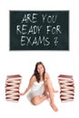 Beautiful young woman sitting between two huge piles of books in front of a blackboard Royalty Free Stock Photo