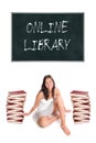 Beautiful young woman sitting between two huge piles of books in front of a blackboard Royalty Free Stock Photo