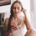 Beautiful young woman sitting on the windowsill listen to music Royalty Free Stock Photo