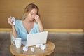 Beautiful young woman sitting on workplace with the laptop and tired crumpling the sheet