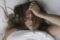 Beautiful young woman sleeping in bed with messy brown hair top view, lying with white bed sheets and freckles Royalty Free Stock Photo