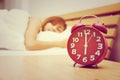 Beautiful young woman sleeping on the bed with red alarm clock i Royalty Free Stock Photo