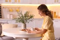 Beautiful young woman with smartphone having breakfast in kitchen. Weekend morning Royalty Free Stock Photo