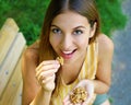 Beautiful young woman smiling and eating nuts outdoor. Healthy concept Royalty Free Stock Photo