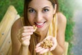 Beautiful young woman smiling and eating nuts outdoor. Healthy concept Royalty Free Stock Photo