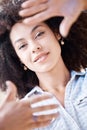 Beautiful young woman smiling and framing her face using her fingers from above. Happy hispanic woman with curly afro Royalty Free Stock Photo