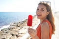 Beautiful young woman smiling with an icicle popsicle in her hand on summer. Looks at camera Royalty Free Stock Photo