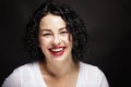 Beautiful young woman with smooth white teeth is laughing. Bright brunette with curly hair. Black background. Close-up Royalty Free Stock Photo