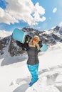 Beautiful young woman snowboarder goes in for winter sports in snowy mountains she stands in snow and holds a snowboard Royalty Free Stock Photo