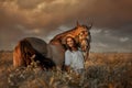 Beautiful young woman on spanish buckskin horse in rue field