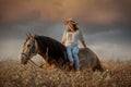 Beautiful young woman on spanish buckskin horse in rue field