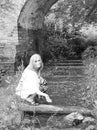 Beautiful young woman splashes water from a stream under an old bridge Royalty Free Stock Photo