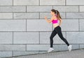Beautiful young woman in sports clothing running while exercising outdoors Royalty Free Stock Photo
