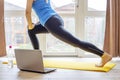 Beautiful young woman in sportswear doing sport exercises on yoga mat at home. Fitness training online with a laptop. Healthy Royalty Free Stock Photo