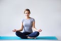 Beautiful young woman in sportswear practicing yoga while sitting in lotus position on gray background. Royalty Free Stock Photo