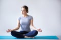 Beautiful young woman in sportswear practicing yoga while sitting in lotus position on gray background. Royalty Free Stock Photo