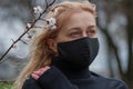 Beautiful young European woman in spring clothes on the street with a medical face mask on. coronavirus - Covid19 Royalty Free Stock Photo