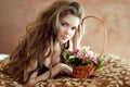 Beautiful young woman with spring flowers and long wavy hair lying on bedroom, beauty portrait, interior Royalty Free Stock Photo