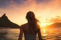 Beautiful young woman standing on the beach and enjoying the sunset, Female surfer rear view in sea at sunset, Oahu, Hawaii,