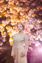 Beautiful young woman standing at blossoming tree in the garden Royalty Free Stock Photo