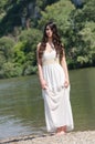 Beautiful young woman standing on the side of a river Royalty Free Stock Photo