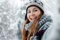 Beautiful young woman standing among snowy trees in winter forest and taking a selfie