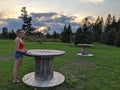 A young woman stands at a table on a grass field at sunset Royalty Free Stock Photo