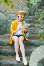 beautiful young woman in straw hat using tablet while sitting on stone staircase Royalty Free Stock Photo