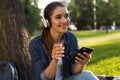 Beautiful young woman student in the park listening music with headphones using mobile phone. Royalty Free Stock Photo